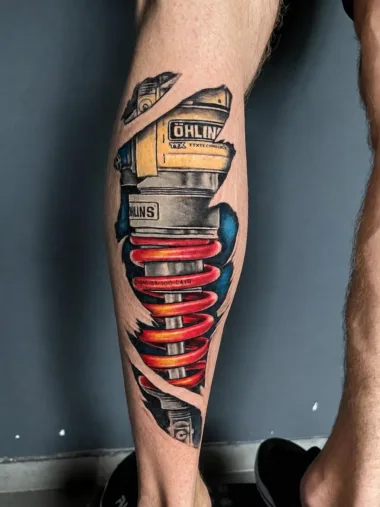 Kolorowy tatuaż amortyzatora na łydce — Dima, Zajawa Tattoo Żary